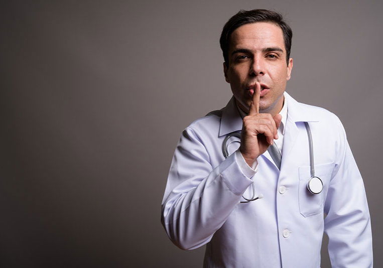 Studio shot of handsome Persian man doctor against gray background